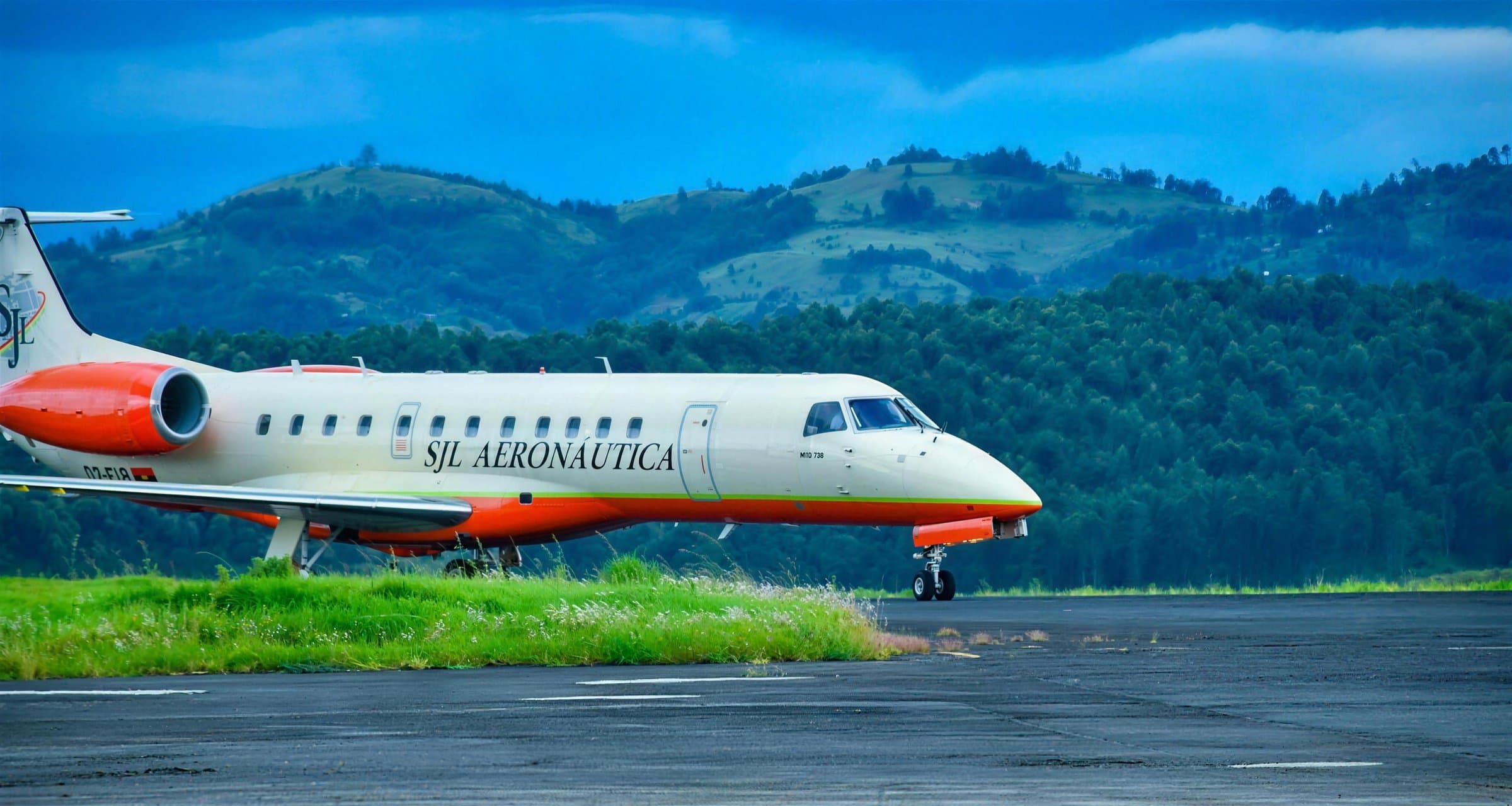 Embraer 135 da SJL com livraria creme e laranja em frente às colinas